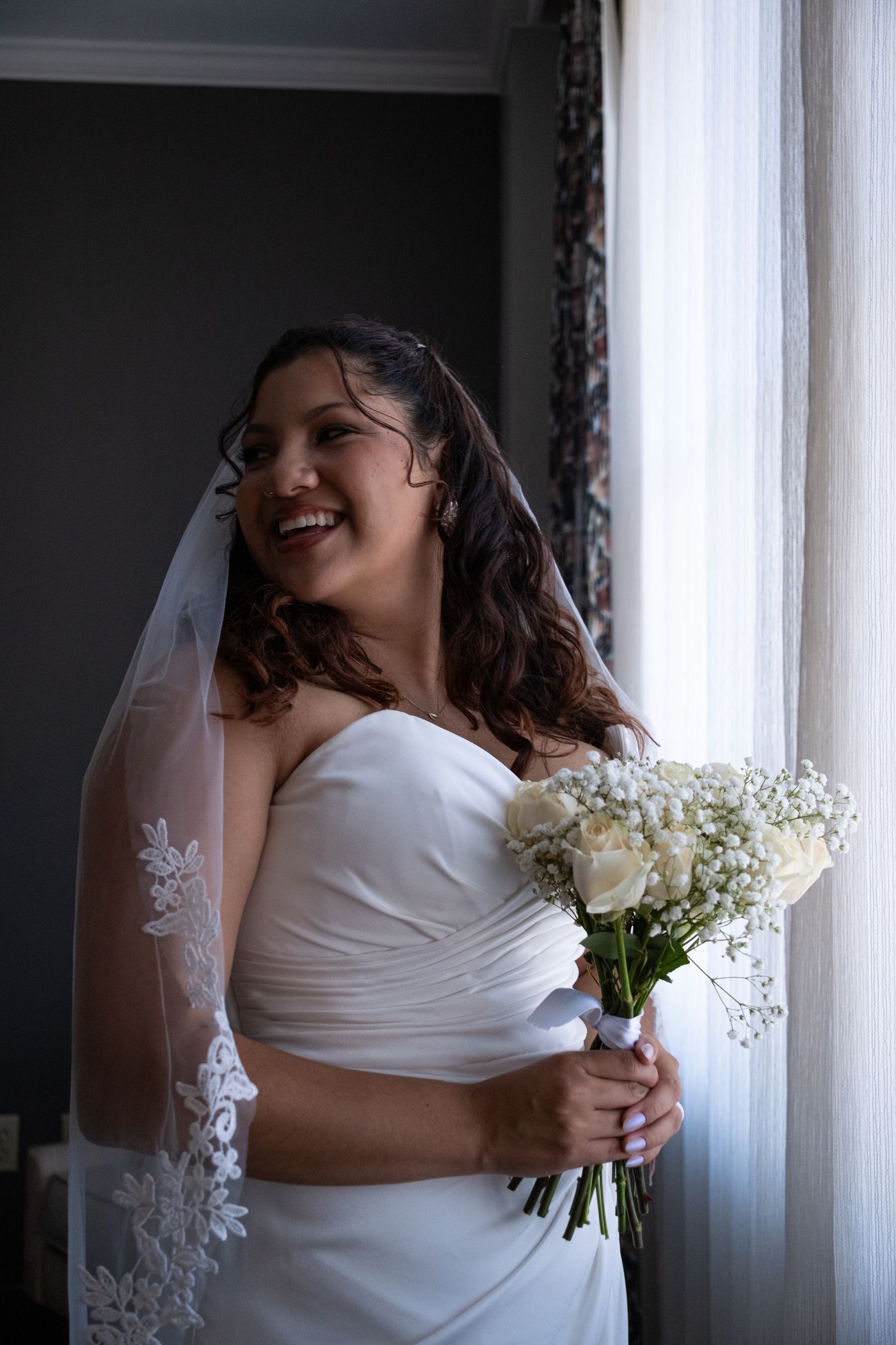 Bride holding a bouquet by a window